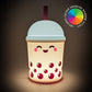 A cute boba tea cup shaped night light glowing with warm light, featuring a smiling face and red bubble details, with a color-changing rainbow effect badge in the top right corner.