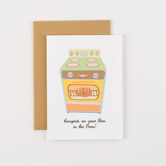 Congrats card that features a stove range with a bread loaf in the oven. Text reads: Congrats on your bun in the oven. 