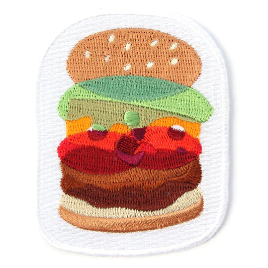 Burger patch with meat, tomato, cheese, lettuce and a sesame seed bun.