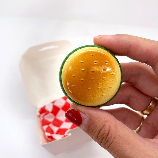 Butane lighter shaped like a hamburger. Shown held in a person's hand for size reference.