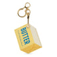A novelty keychain shaped like a stick of butter, featuring a pale yellow body with blue 'BUTTER' text, a cream-colored side panel, and gold-tone metal hardware including a lobster clasp and key ring, shown on a plain white background.