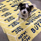 Dog sitting on 5 stacked butter rugs.