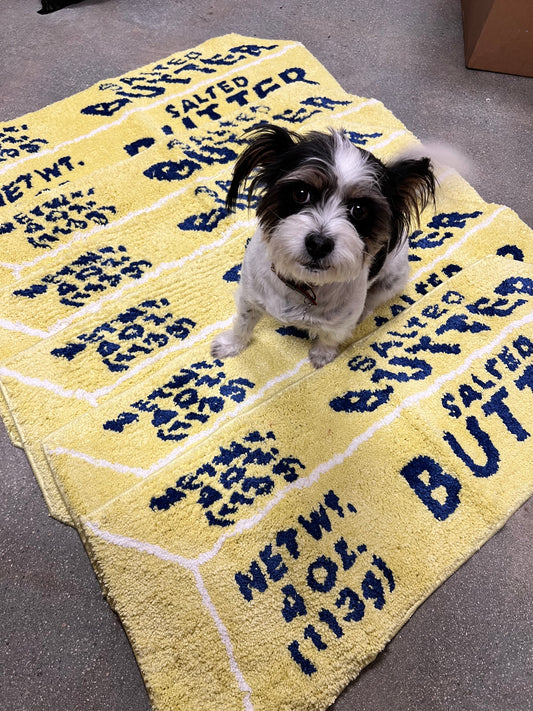 Dog sitting on 5 stacked butter rugs.