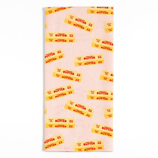 Tea towel with all-over print of 4oz. sticks of unsalted butter on pale pink background.