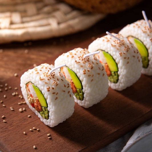 Three sushi roll candles with avocado and crab on a wooden board.