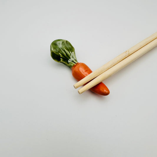 Carrot Chopstick Rest with a pair of chopsticks resting on it.