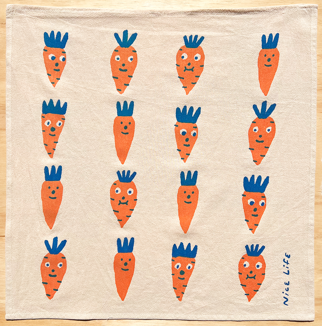 Beige towel with cartoon carrot pattern on a wooden surface
