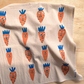Beige towel with cartoon carrot pattern on a wooden surface