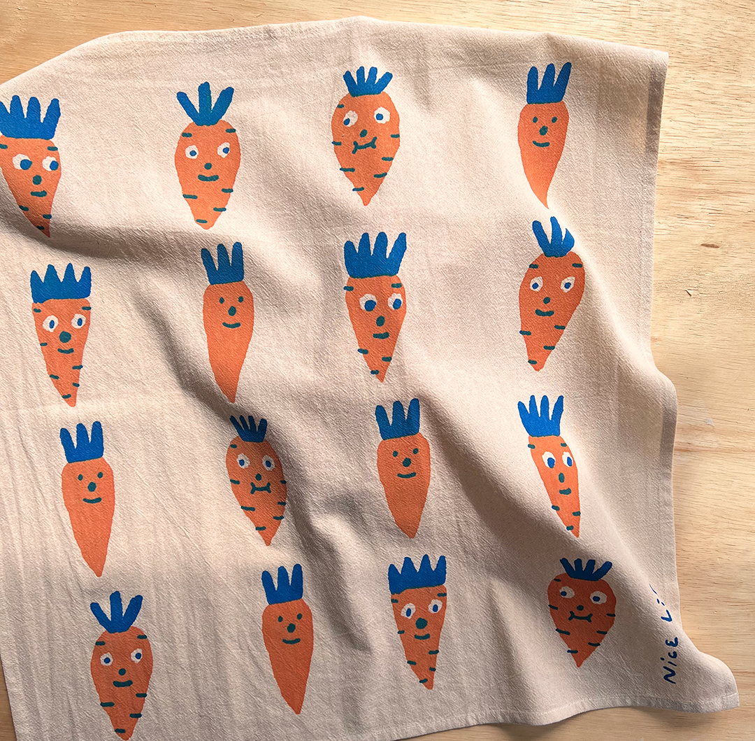 Beige towel with cartoon carrot pattern on a wooden surface