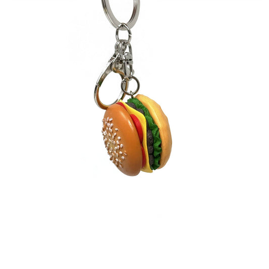 Keychain shaped like a cheeseburger with sesame seed bun, tomato, sliced cheese, burger and lettuce. Metal clasp.