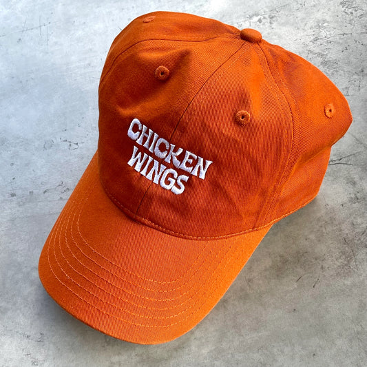 Buffalo sauce colored dad hat with text that reads: Chicken Wings