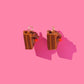 Chocolate Cake Slice earrings on a pink background