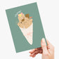 A hand holding a greeting card with a humorous illustration of churros bundled in a cone with faces, and the text 'churray!' on a light gray background.