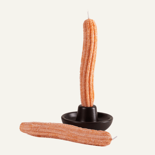 2 candles that look like Churros. One is laying down and the other is in a brown candle holder.