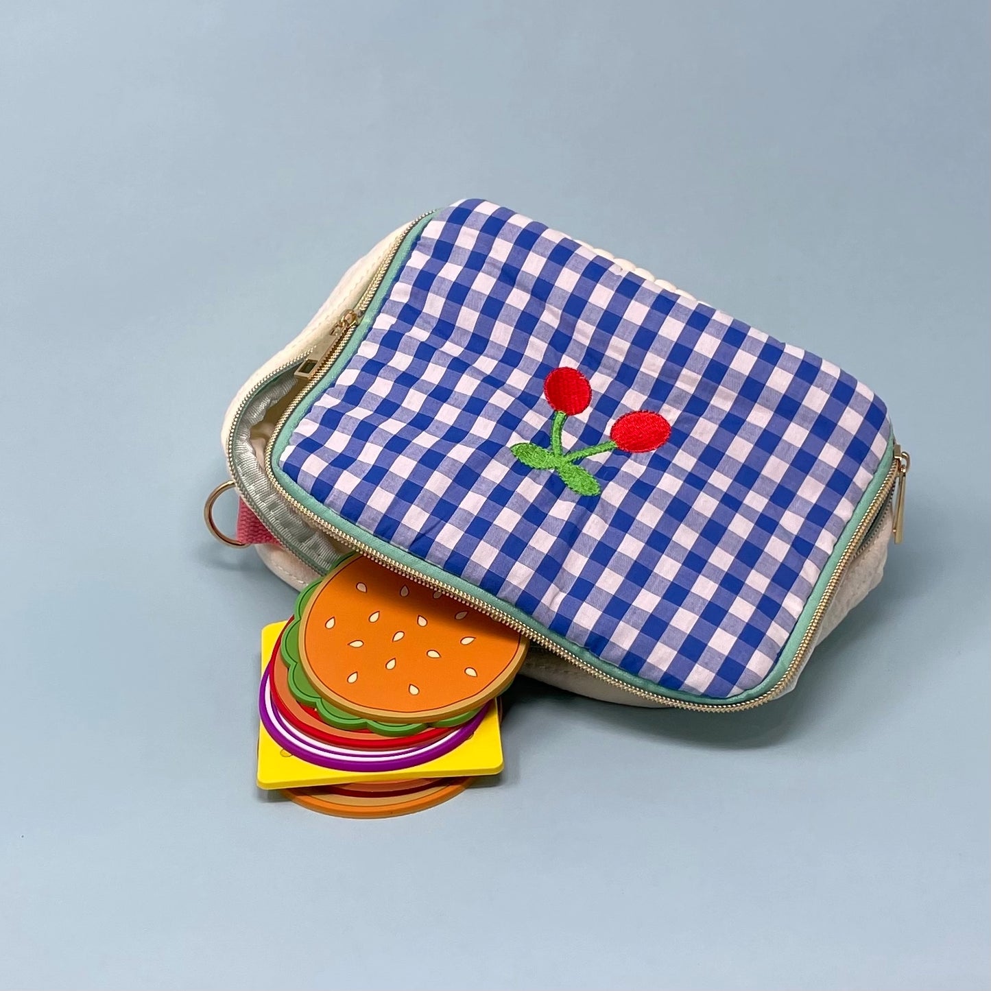 Little blue checkered bag with a cherry on it unzipped to reveal an 8pcs cheeseburger coaster set.