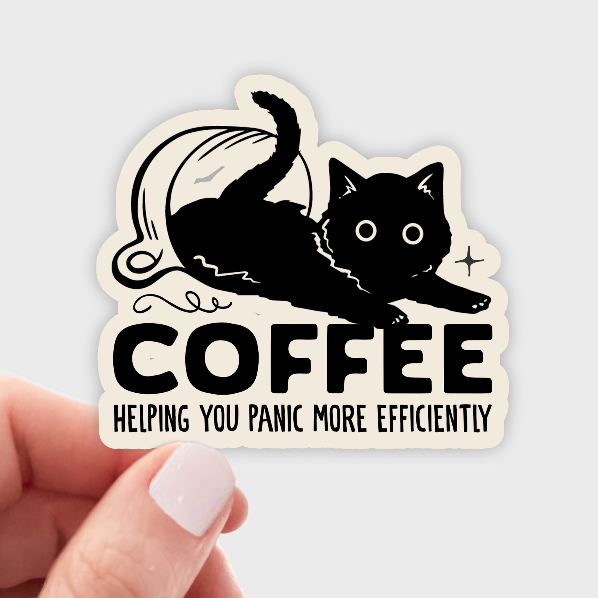 A hand with light pink nail polish holds a die-cut sticker featuring a black cat stretching over the word 'COFFEE' with the phrase 'HELPING YOU PANIC MORE EFFICIENTLY' on a light gray background.