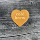 Heart-shaped 'cold brew' sticker on a wooden surface