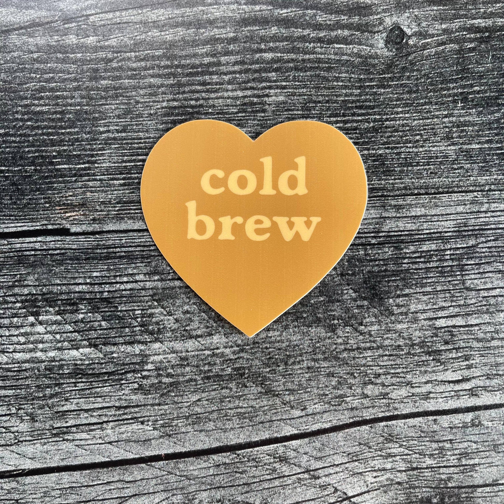 Heart-shaped 'cold brew' sticker on a wooden surface