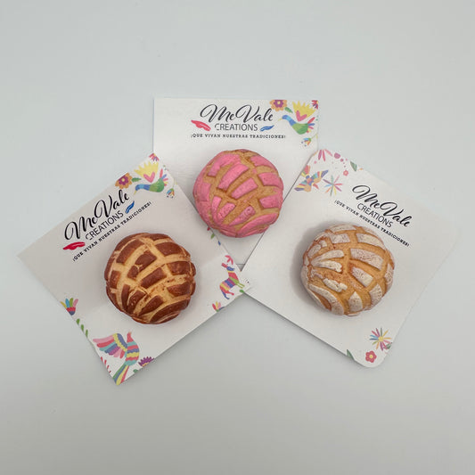 Three concha magnets on card backings that say Me Vale Creations. Concha flavors are strawberry, vanilla and chocolate.