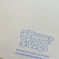 A close-up of textured off-white paper with blue hand-screen printed text reading 'ALPHABET STUDIOS' and smaller text below reading 'hand screen printed alphabetstudios.com'.