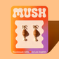 Croissant earrings on a 'MUSH' branded card with a gradient background