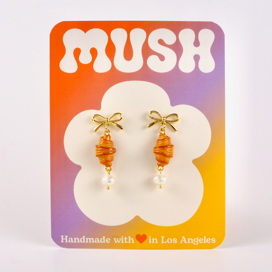 Pair of earrings on a 'MUSH' branded card with a gradient background