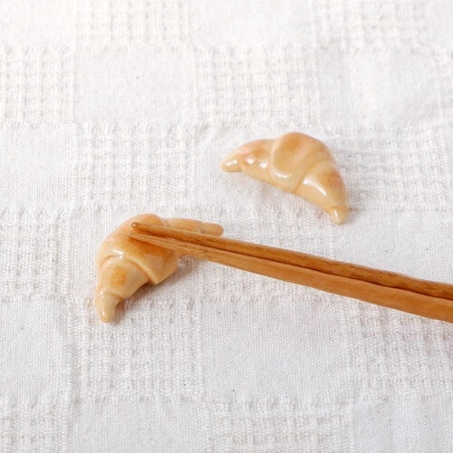 2 Croissant chopstick holders with chopsticks on it.