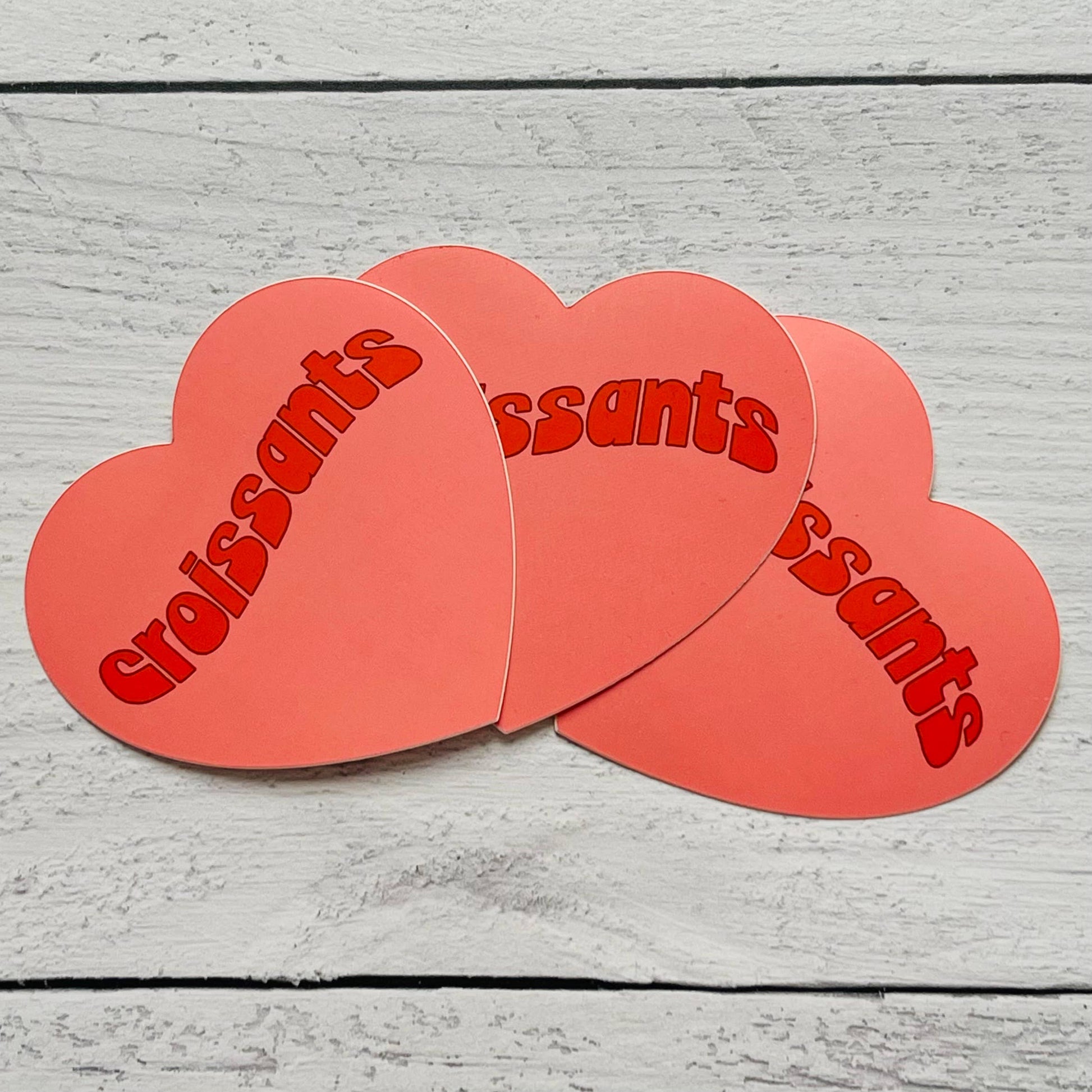 Heart-shaped sticker with "croissants" text in red retro font.