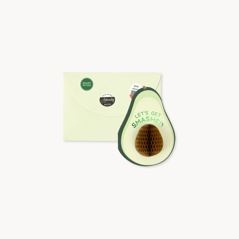 Picture of die-cut avocado  greeting card with text "Let's Get Smashed," comes with green envelope featuring faux grocery store stickers.