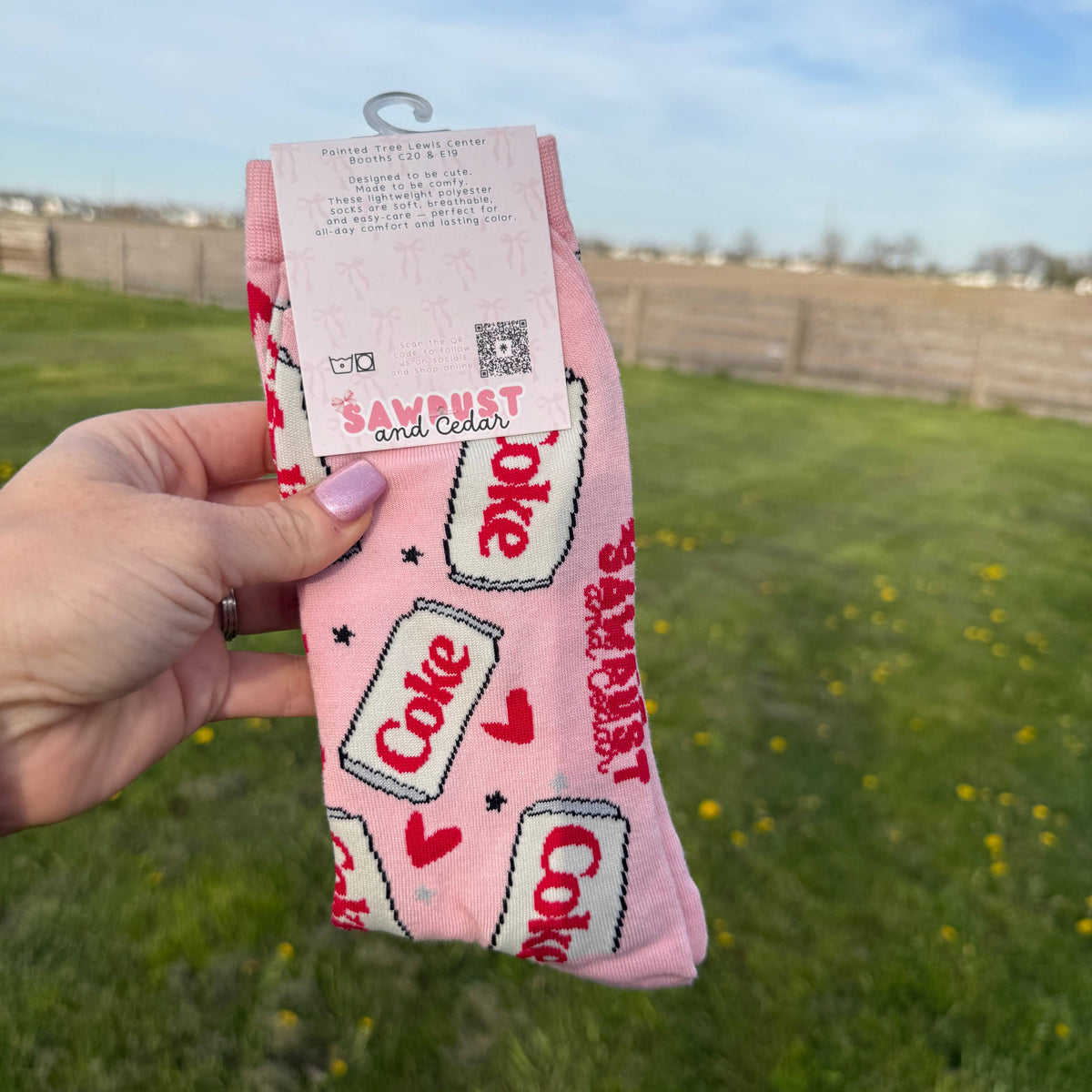 Pink product with 'Coke' branding held against a grassy outdoor background