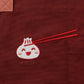 Cinnamon colored apron with mauve straps. This apron has a design that is dedicated to Dim Sum and has a steamer basket full of smiling dumplings and one dumpling being grabbed by chopsticks.