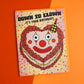 Birthday card with clown face design on an orange background