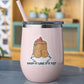 A light pink insulated stemless tumbler with a clear lid and straw, featuring a cartoon tater tot graphic and the text 'DROP IT LIKE IT'S TOT' on the front, set against a softly blurred indoor background.