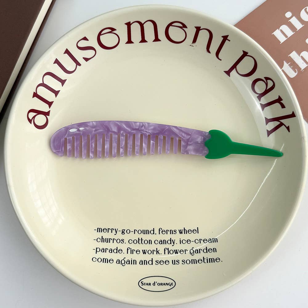 Decorative plate with 'amusement park' text and a purple, eggplant shaped comb on a white background