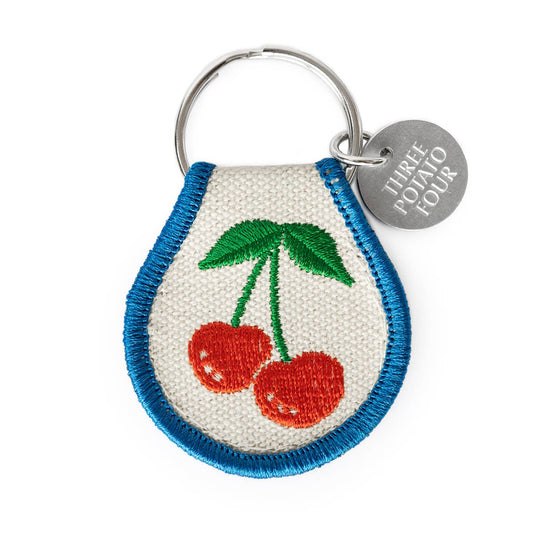 Embroidered Cherry Keychain. Duo cherries with leaves with a blue border. Keyring has an additional metal piece that says: Three Potato Four.