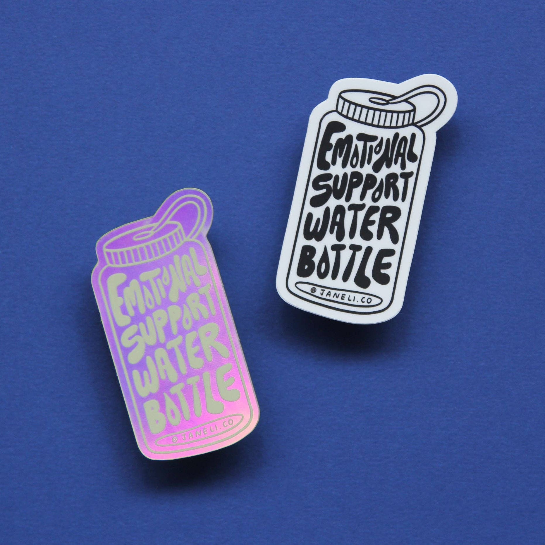 Two stickers shaped like water bottles on a solid blue background. One is holographic pink and purple with the text 'EMOTIONAL SUPPORT WATER BOTTLE' in light pink.