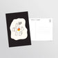 A postcard product shown on a light gray background, with one front-facing postcard featuring a black background, with simple ghost illustrations including one in orange, yellow, and white, like a candy corn, and a second blank postcard behind it with printed postcard text.