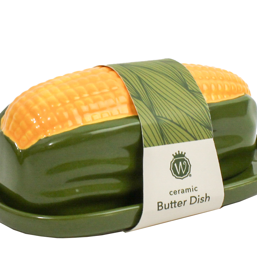 A ceramic butter dish shaped like a corn cob, featuring a glossy dark green base and a bright yellow-orange corn tip, wrapped in a paper band with the brand name 'W' and 'ceramic Butter Dish' printed on it.