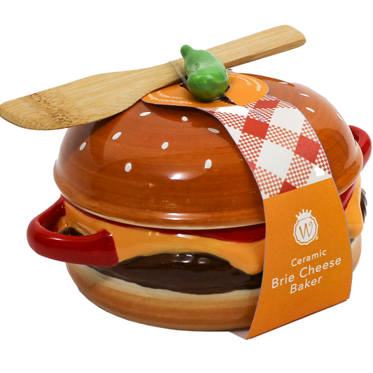 A ceramic brie cheese baker shaped like a hamburger, with a wooden spatula resting on top and a paper tag reading 'Ceramic Brie Cheese Baker' on a white background.