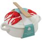 White ceramic Brie cheese baker with a lid decorated with red lobster illustrations, featuring a wooden spatula resting on top and a teal paper tag.