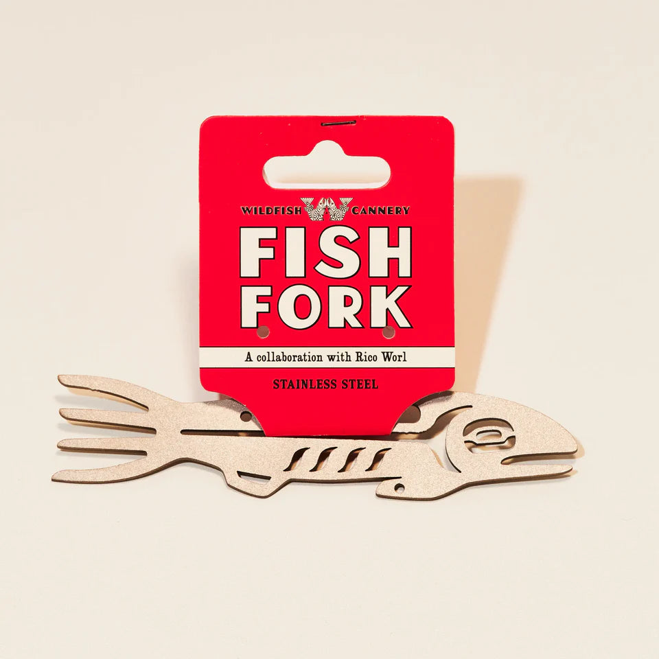 Stainless steel fish-shaped fork with red packaging on a beige background