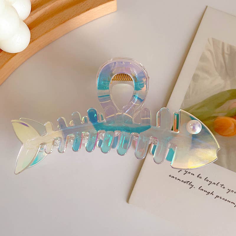 Iridescent fish-shaped hair clip on a light surface