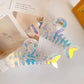 Holographic fish-shaped hair clips on a light surface with a photo frame in the background.