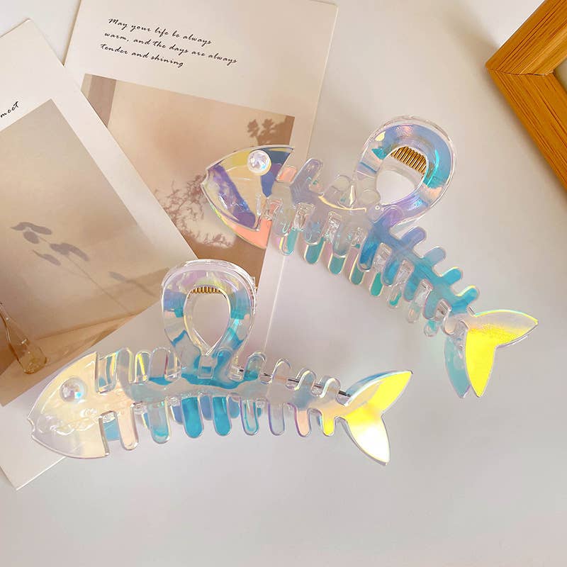 Holographic fish-shaped hair clips on a light surface with a photo frame in the background.