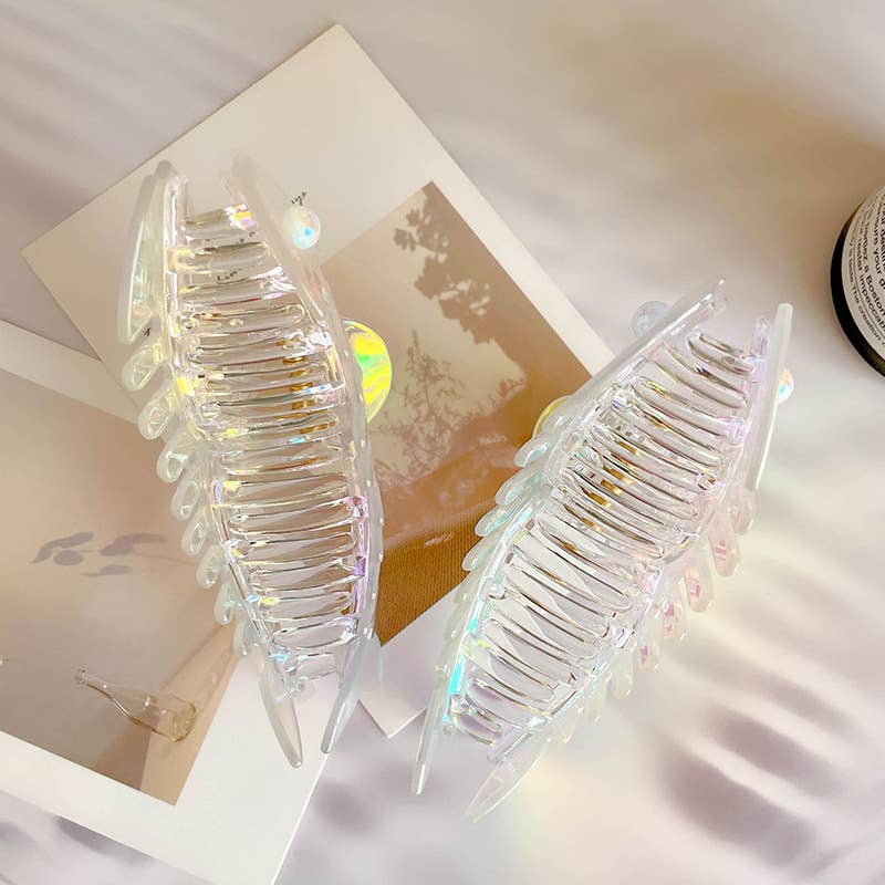 Iridescent fish shaped hair claws with fake pearl details on a light background