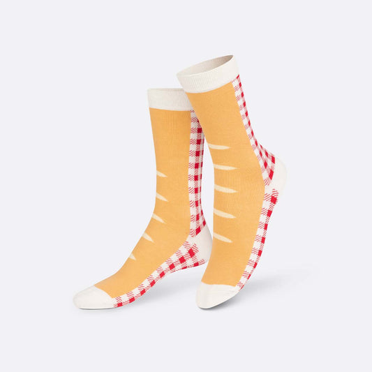 Pair of yellow socks with red and white checkered pattern on a light gray background