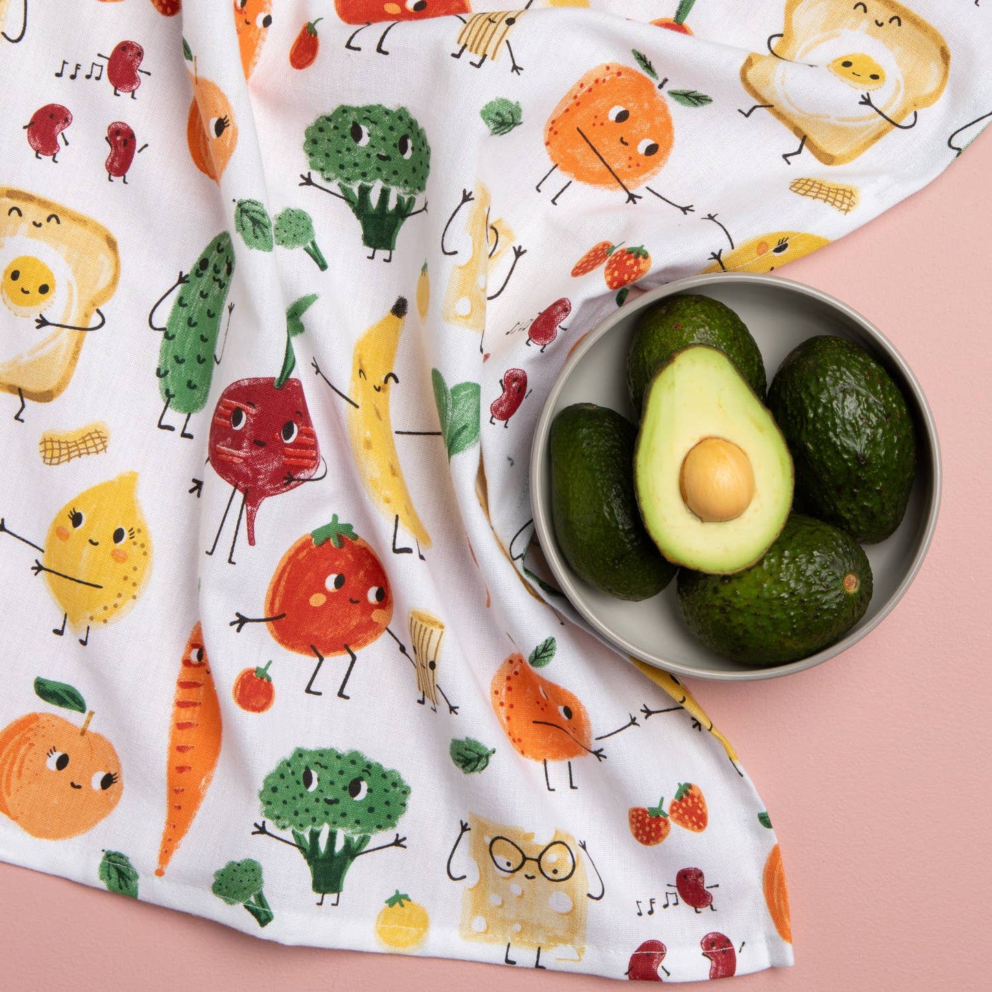 Avocados in a bowl on a colorful fabric with cartoon food characters