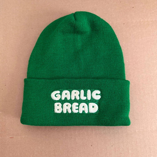 Green beanie with 'Garlic Bread' text on a beige background