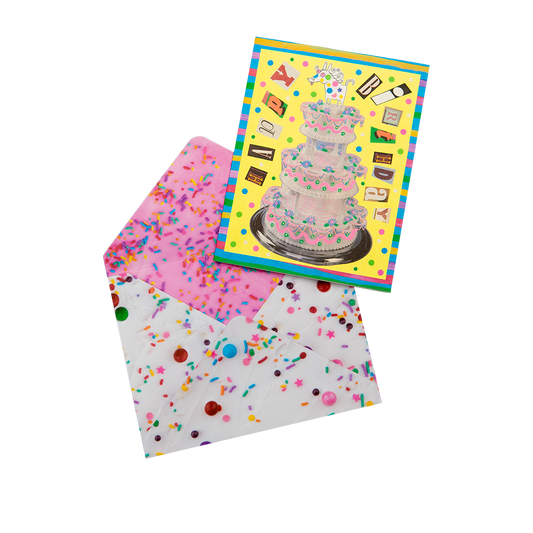 Greeting card with a cake illustration and a matching envelope with colorful confetti pattern on a white background.