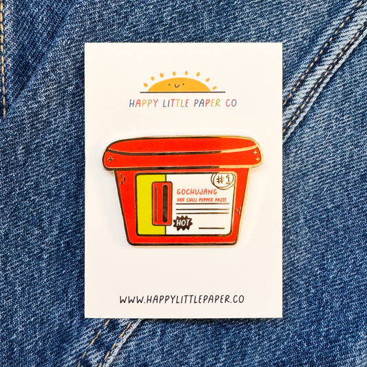 Sticker of a red container with yellow accents on a white background, placed on blue denim fabric.